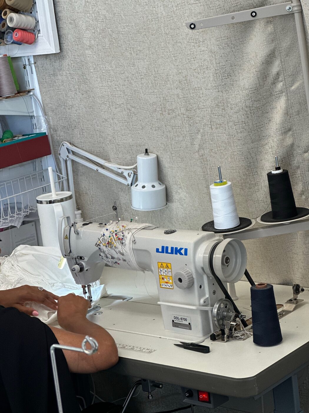Tailor stitching a garment on a sewing machine at KYM Amen