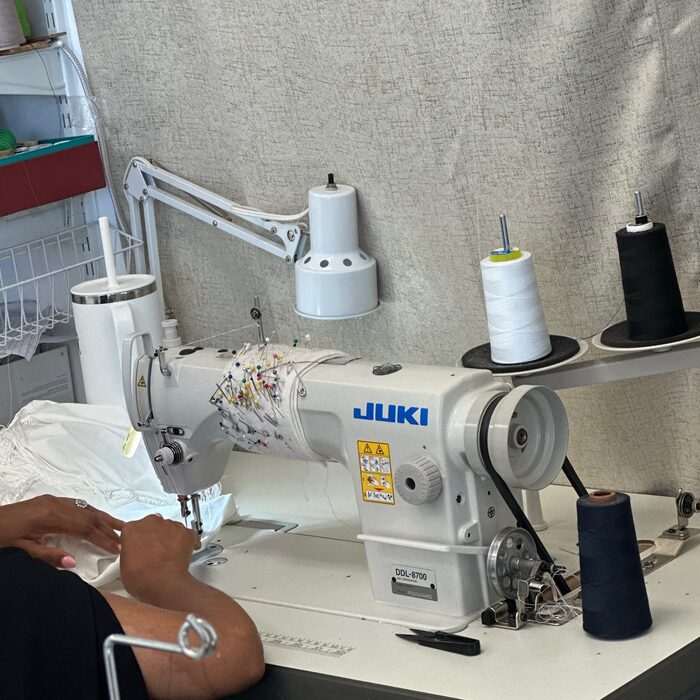 Tailor stitching a garment on a sewing machine at KYM Amen